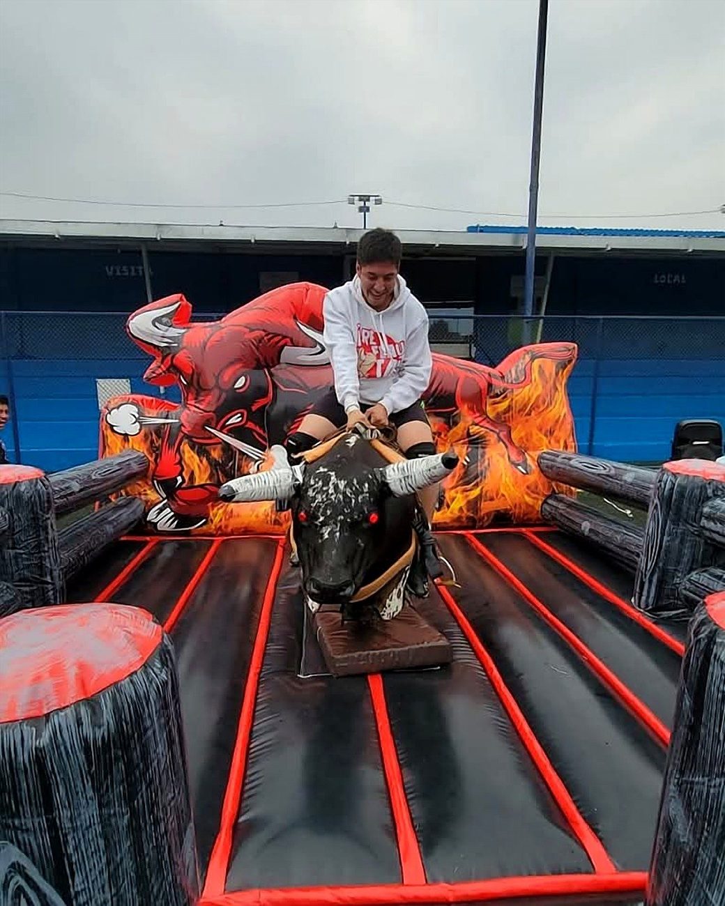 Invitado riendo mientras monta el toro mecánico en evento deportivo